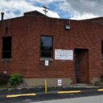 Exterior view of a multi-story red brick industrial building with signs reading "Berkley Surgical," "Berkley Packaging," and "United Converting," featuring a paved driveway lined with yellow parking bumpers and "No Parking" sign on Virginia Avenue, Uniontown, PA.